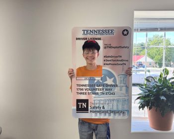 Student holds a giant Tennessee driver license prop