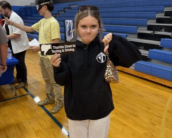 Student gives a thumbs down to texting and driving in a gym