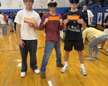 Students wearing Fatal Vision goggles hold iDont signs in a gym